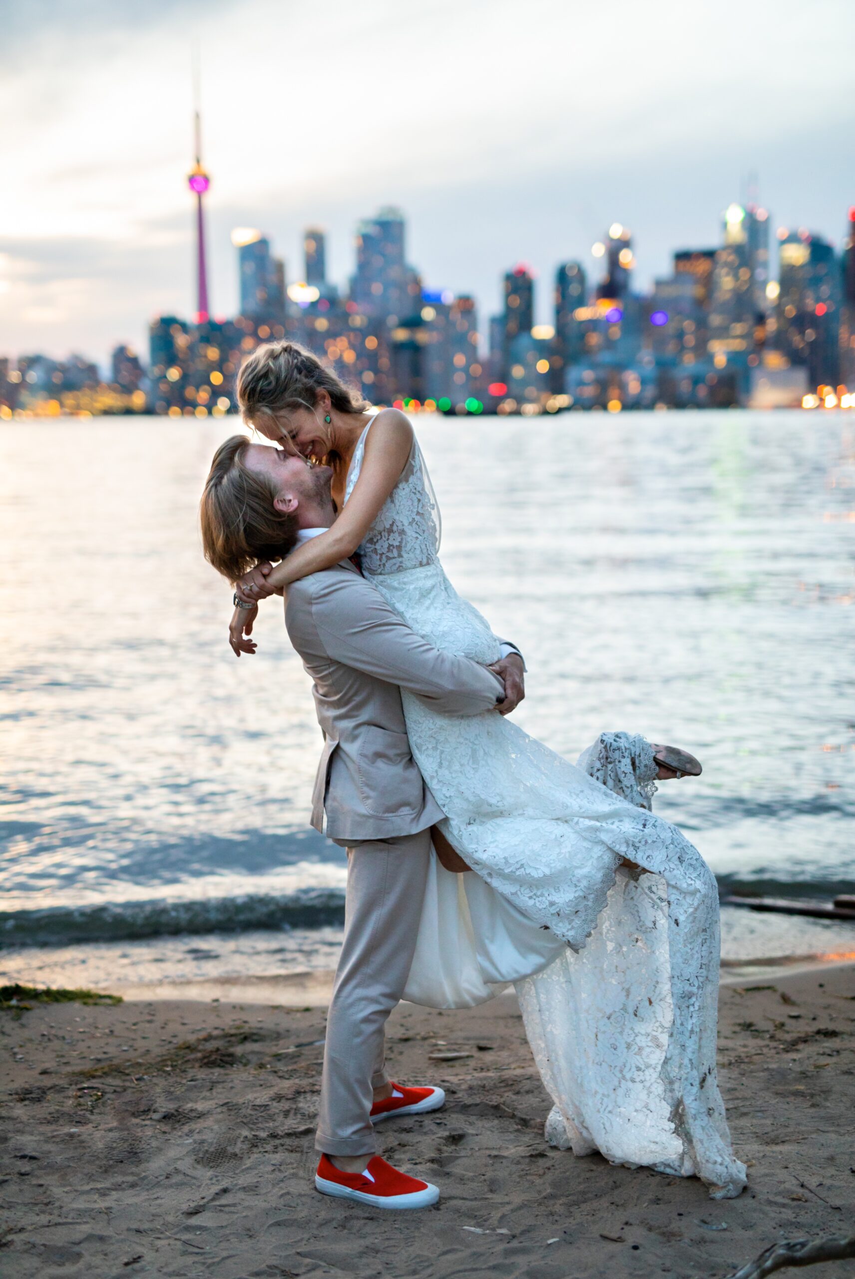 Groom lifts up bride kiss in front of Toronto skyline sunset