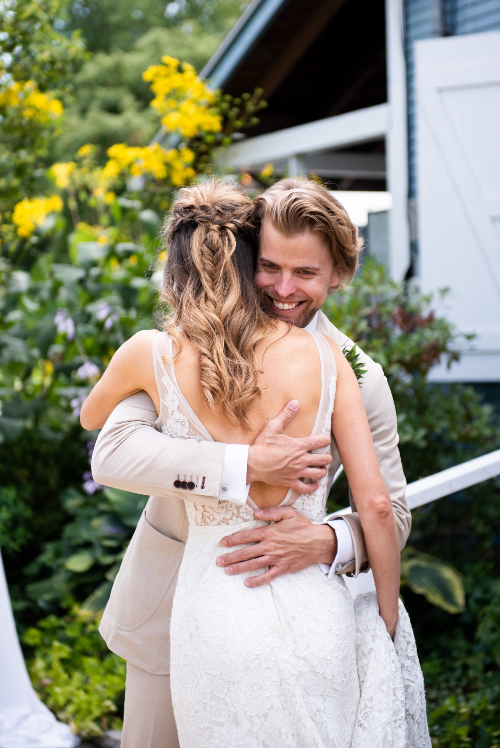 Groom smiles at bride, Lace wedding dress, boho braided wedding hair
